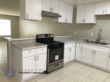 Costa Mesa apartment for rent - A kitchen with white cabinets and a black stove top oven.