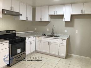 Costa Mesa apartment for rent - A kitchen with white cabinets and a black stove top.