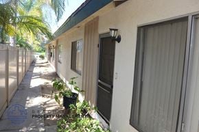 Costa Mesa apartment for rent - A sunny day at the BE Property Management building with a row of houses and plants.