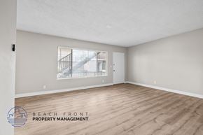 Anaheim apartment for rent - A spacious room with wooden flooring and a large window overlooking a balcony.