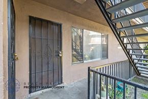 Anaheim apartment for rent - A staircase with a metal railing leads up to a window on a building.
