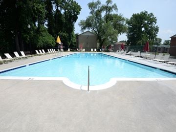 Baltimore apartment for rent - A large outdoor swimming pool surrounded by trees and lounge chairs.