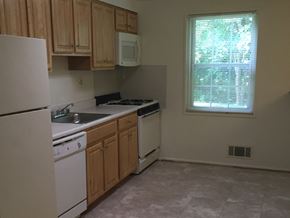 Baltimore apartment for rent - A kitchen with white appliances and wooden cabinets.