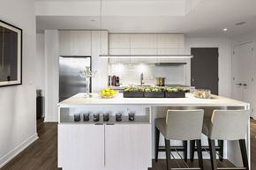 Toronto apartment for rent - A modern kitchen with a white island and two chairs.