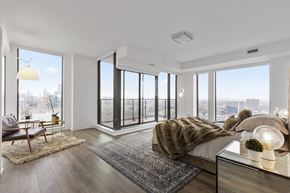 Toronto apartment for rent - A modern bedroom with a large bed and a view of the city.