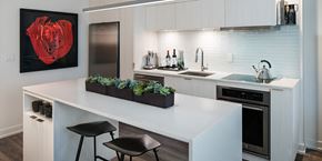 Toronto apartment for rent - A kitchen with a white counter top and black stools.
