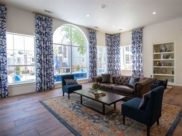 Irving townhouse for rent - A living room with a brown leather couch, a blue chair, and a coffee table with a vase of flowers on it.