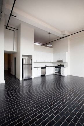 Newark apartment for rent - Open layout kitchen with stainless steel appliances, white cabinets, and black tiled modern floors