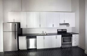 Newark apartment for rent - an empty kitchen with white cabinets and a stainless steel refrigerator