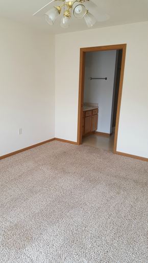 Sun Prairie apartment for rent - an empty living room with carpet and a door to a bathroom