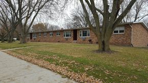 Sun Prairie apartment for rent - the front of a brick house with trees and a sidewalk