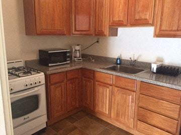 San Francisco townhouse for rent - A kitchen with wooden cabinets and a white stove.