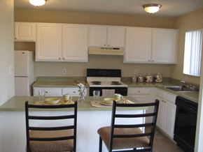 Arvada apartment for rent - a kitchen with white cabinets and a table with two chairs