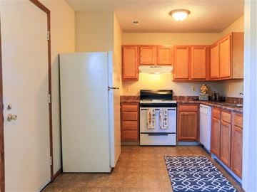 Grove City apartment for rent - A kitchen with a white fridge and wooden cabinets.