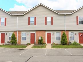 Grove City apartment for rent - A building with red doors and windows with bushes in front.