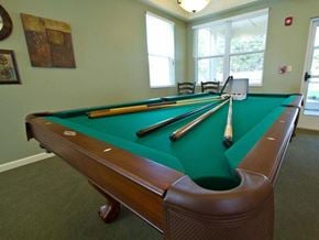 Wauchula apartment for rent - Community game room featuring a full-size pool table, natural light from large windows, and comfortable seating nearby.