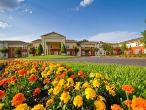 Wauchula apartment for rent - Exterior view of Chatham Pointe apartments community with landscaped grounds, colorful flowers in the foreground, and a modern residential building with covered entrance.