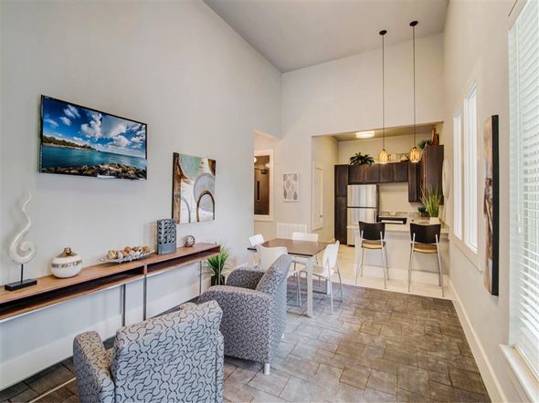 Balcones Heights apartment for rent - A living room with a grey patterned chair and a wooden shelf with decorative items.