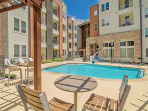 Balcones Heights apartment for rent - A pool surrounded by chairs and buildings.