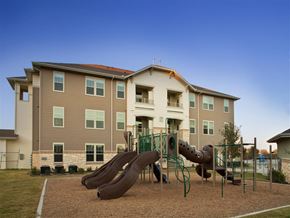 Fort Worth apartment for rent - A playground with a slide in front of a large apartment building.