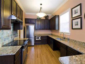 Houston apartment for rent - A kitchen with dark wood cabinets and granite countertops.