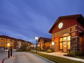 Houston apartment for rent - A building with a clock on the front has a lit up entrance.