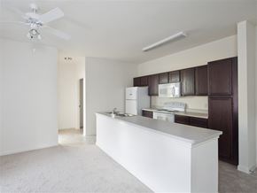 Houston apartment for rent - A white kitchen with a white counter and a white fridge.