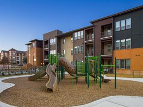 Fort Worth apartment for rent - Community playground featuring climbing structures, slides, and open play areas, providing a family-friendly outdoor space surrounded by landscaped grounds and apartment buildings.