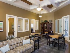 Fort Worth apartment for rent - Resident clubhouse lounge featuring comfortable seating, dining tables, decorative shelving, and private office spaces with large windows and coffered ceilings.
