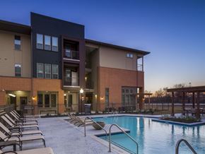 Fort Worth apartment for rent - Resort-style swimming pool featuring lounge seating, in-water tanning ledges, and a spacious pool deck surrounded by apartment buildings and outdoor gathering areas.