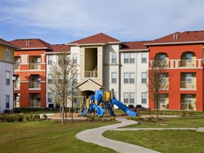 Laredo apartment for rent - A playground with a blue slide is in front of apartment buildings.