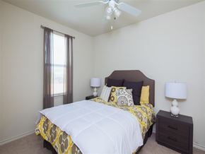 San Marcos apartment for rent - Bedroom with a bed, nightstands, table lamps, and a large window, creating a bright and comfortable sleeping space with neutral finishes and carpeting.