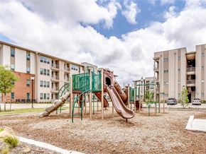 Dallas apartment for rent - A playground with a brown slide and green railing in front of apartment buildings.