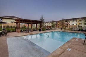 San Antonio apartment for rent - A large outdoor swimming pool surrounded by a patio area with chairs and a pergola.