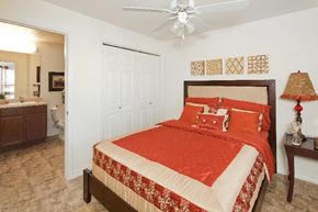 San Antonio apartment for rent - A bedroom with a red bedspread and a ceiling fan.