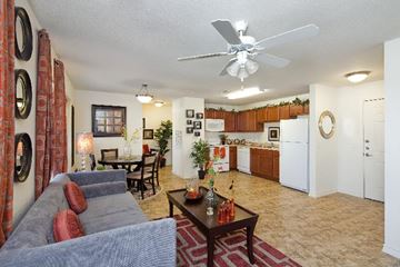 San Antonio apartment for rent - A living room with a grey couch and a ceiling fan.