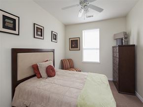 Fort Worth apartment for rent - A bedroom with a bed, dresser, and a ceiling fan.