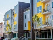 Newark apartment for rent - a new apartment building with yellow and gray facade and cars parked outside