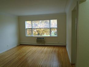 St Paul apartment for rent - an empty living room with a large window and wooden floors