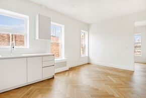 Brooklyn apartment for rent - an empty kitchen with white cabinets and a window