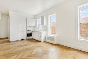 Brooklyn apartment for rent - a renovated kitchen with white cabinets and a wood floor