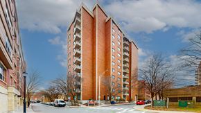 Malden apartment for rent - A tall red brick building with a parking lot in front.