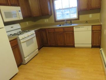 Anoka apartment for rent - an empty kitchen with wooden floors and white appliances