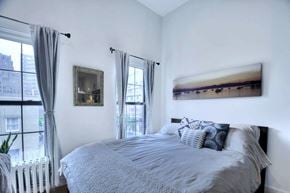 New York apartment for rent - a bedroom with a bed and two windows and a painting on the wall