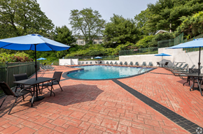 Norwich apartment for rent - A pool surrounded by a brick patio and blue umbrellas.