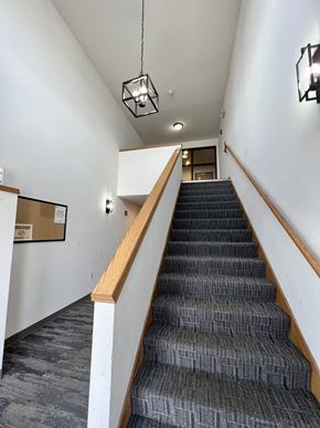 Reedsburg apartment for rent - A staircase with a wooden handrail and a grey carpeted runner.