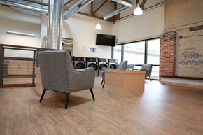 Madison apartment for rent - a lounge area with chairs and a tv in a room with a brick wall and