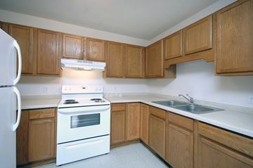 Bloomington townhouse for rent - an empty kitchen with wooden cabinets and white appliances