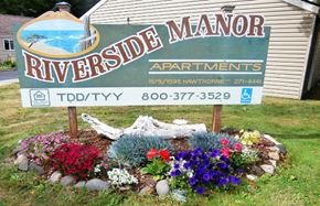 Reedport apartment for rent - a sign for riverside manor apartments in front of a flower garden