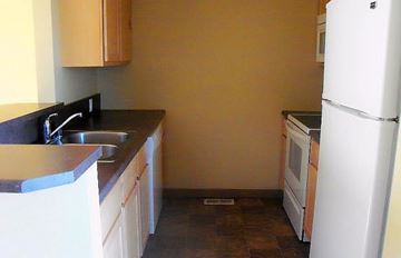 Cutbank apartment for rent - a small kitchen with a sink and a refrigerator